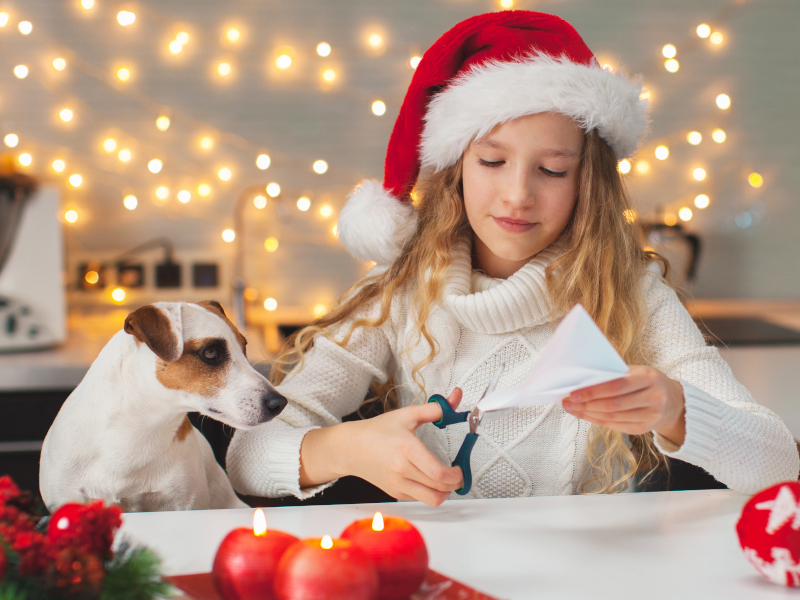 Girl making Christmas crafts with her dog watching