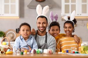 Happy African American family with Easter eggs at table in kitchen