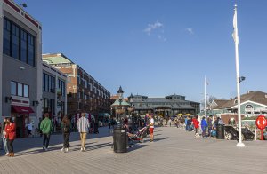 Alexandria, VA, USA 11-29-2020: A sunny day in the waterfront district of historic Alexandria with people walking by the Potomac river. There are shops and flags on sides of this pedestrian only site.