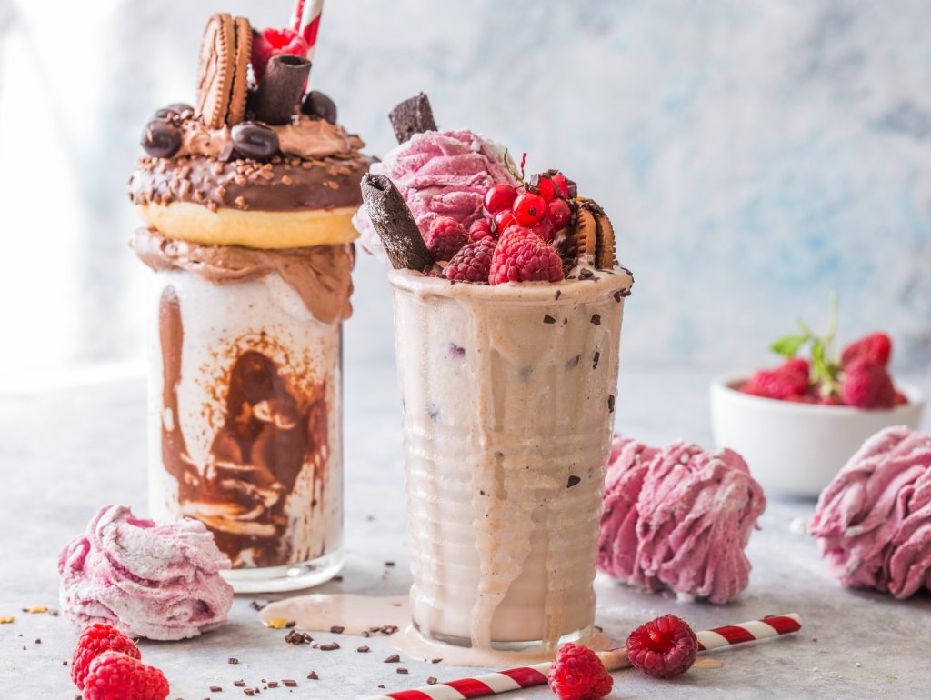 Chocolate indulgent frosting exreme milkshake with donut and sweets. Crazy freakshake food trend. Copy space. Feakshake. Chocolate indulgent frosting exreme milkshake