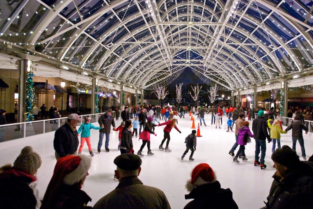 The best places to lace up your ice skates in the DMV Children and adults skating beneath string lights at Reston Town Center Ice Rink, one of the ice skating rinks DMV families can enjoy.