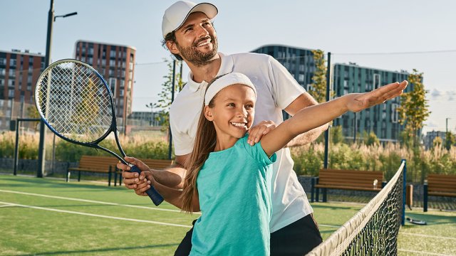 Save Download Preview Tennis lesson for a child. Tennis coach teaches little girl to play tennis on grass court