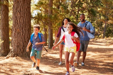 Children Running Ahead Of Parents On Family Hiking Adventure