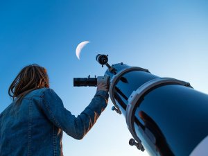 Seeing Stars: Summer Astronomy Events for Families in the DC Area A parent and child at a family stargazing event near DC, looking through a telescope at the moon.