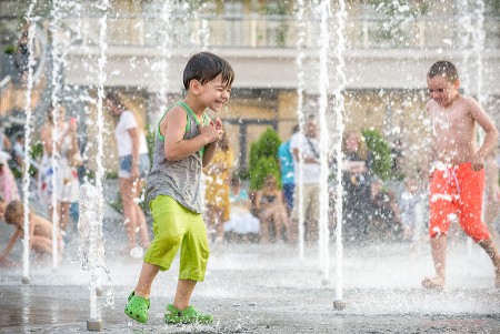 Children playing in an outdoor splash pad for the July summer fun guide featuring DMV family events.