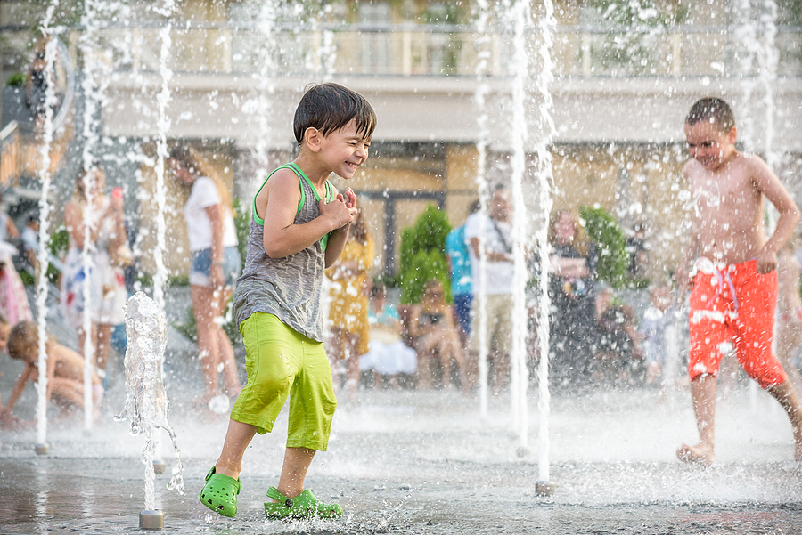 Children playing in an outdoor splash pad for the July summer fun guide featuring DMV family events.