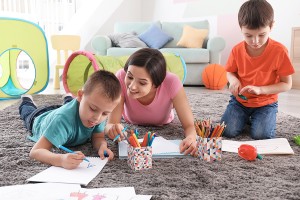 How is an au pair different from a nanny? Two little boys drawing with nanny at home