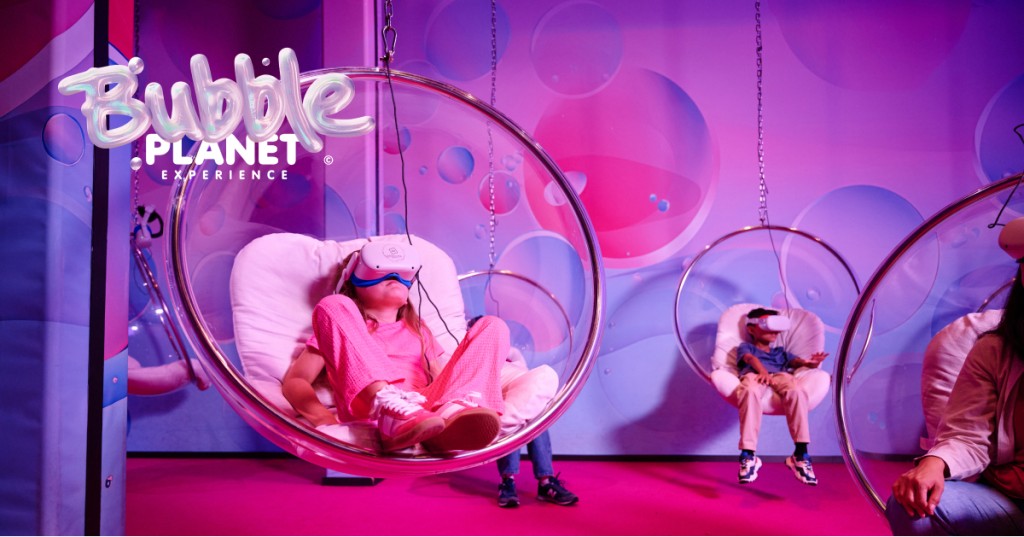 Visitors pose inside oversized transparent bubbles in a colorful room at Bubble Planet DC.