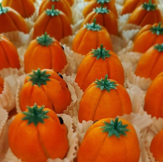 Halloween desserts shaped like orange pumpkins with green stems, lined up in paper cups at Heidelberg Pastry Shoppe in Arlington, Va.