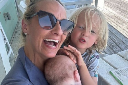 Lauryn Ricketts smiles while holding her baby beside her young son on a porch.