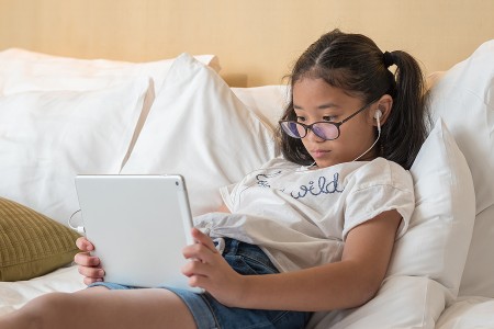 School Asian girl kid using screen time as a reward
