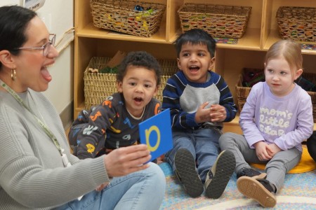 A teacher at Lowell School, a progressive school in DC, models a letter sound for three of the youngest students during phonics.